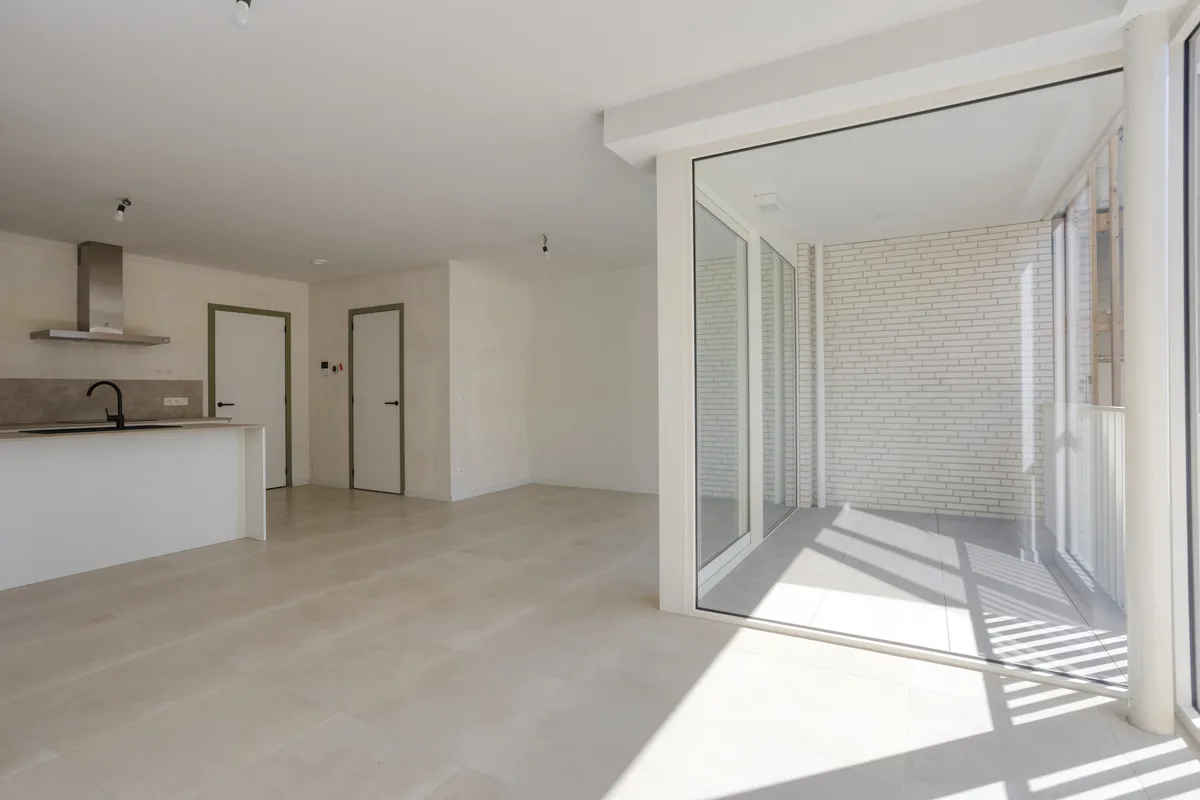 Open leefruimte met keuken en schuifdeuren naar het terras