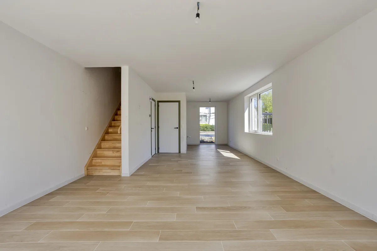 Leefruimte van een woning met houten trap en tuindeur